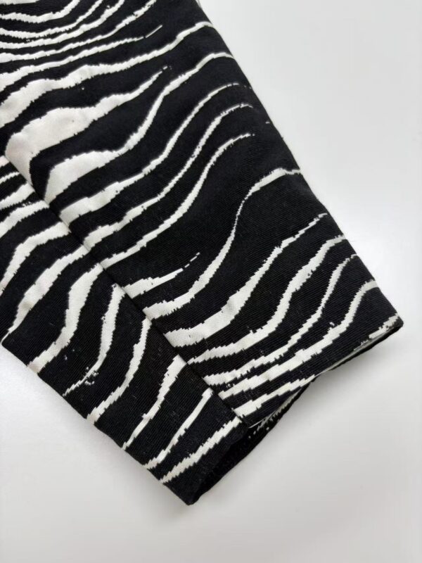 Close-up of black and white zebra print fabric, showcasing bold stripes suitable for stylish clothing and accessories.