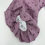 Close-up of a pink pajama sleeve with small heart patterns and a white elastic cuff, showcasing comfortable loungewear design.