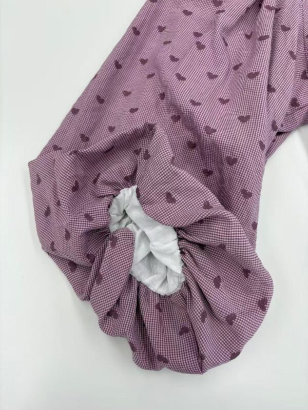 Close-up of a pink pajama sleeve with small heart patterns and a white elastic cuff, showcasing comfortable loungewear design.