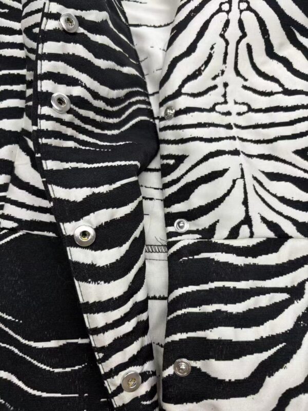 Close-up of a stylish zebra print jacket with silver buttons, showcasing bold black and white pattern perfect for fashion-forward outfits.