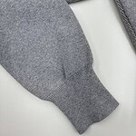 Close-up of a gray knit sweater sleeve showing detailed fabric texture and ribbed cuff.
