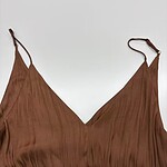 Close-up of a stylish brown dress with thin straps and pleated fabric, perfect for casual or formal occasions.