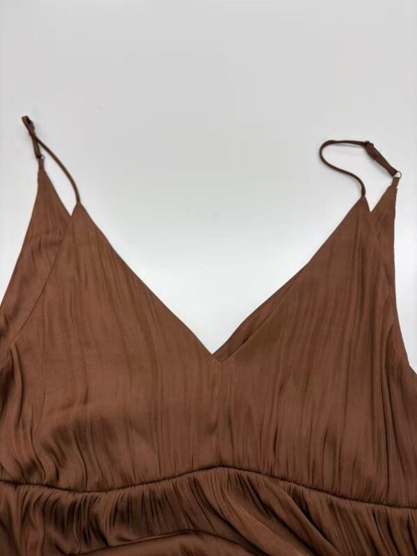 Close-up of a stylish brown dress with thin straps and pleated fabric, perfect for casual or formal occasions.