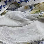 Close-up of floral and blue patterned bedding with white sheets, showcasing intricate designs and soft fabric textures.