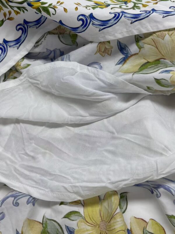 Close-up of floral and blue patterned bedding with white sheets, showcasing intricate designs and soft fabric textures.