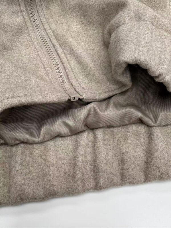 Close-up of a grey hoodie featuring a zipper and soft fabric, ideal for casual wear and comfortable fashion.
