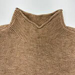 Close-up of a brown knitted turtleneck sweater, showcasing its texture and design, perfect for fall and winter fashion.