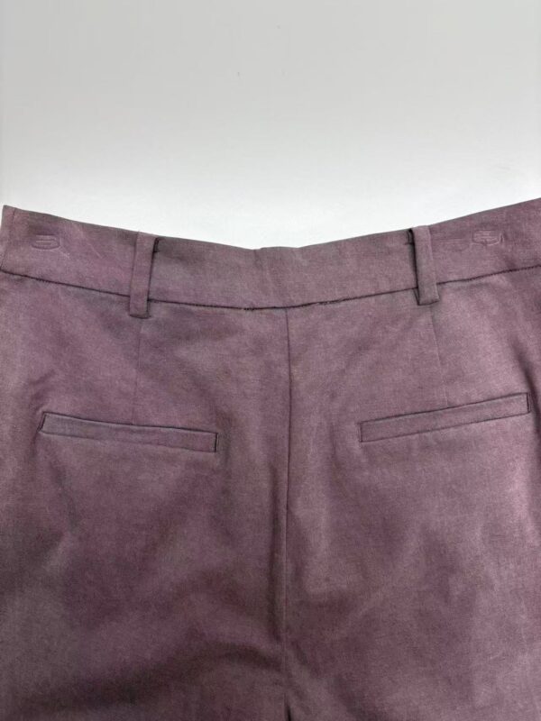 Close-up of mauve dress pants with belt loops and back pockets, suitable for formal or business wear.