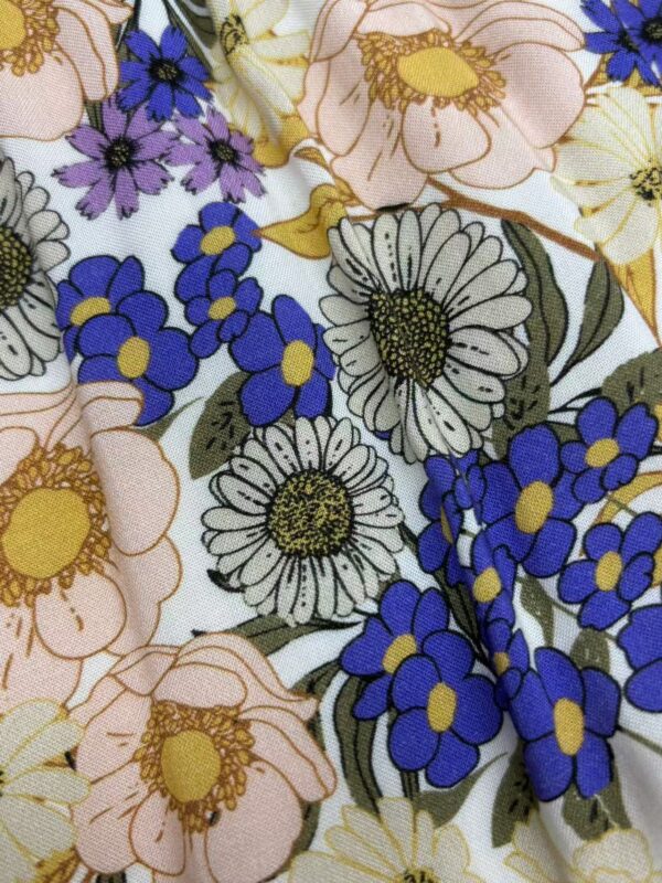 Close-up of a floral fabric pattern featuring pink, white, purple, and blue flowers with green leaves, ideal for fashion and textile projects.