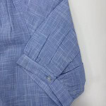 Close-up of a men's blue checkered dress shirt with buttoned sleeve and collar detail, suitable for formal or business wear.