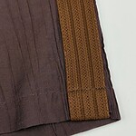 Close-up of traditional brown fabric with orange woven border, showcasing intricate textile craftsmanship and vibrant color contrast.