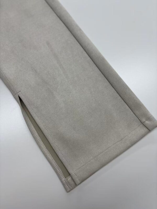Close-up of beige pants with zipper detail at the hem, showcasing smooth fabric and clean stitching, ideal for fashion and clothing SEO.