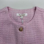 Close-up of a pink tweed women's jacket with a gold button, showcasing elegant fashion suitable for stylish occasions.