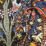 Close-up of a vibrant, floral-patterned shirt with detailed embroidery, buttons, and a mix of bright colors including orange, yellow, blue, and green.
