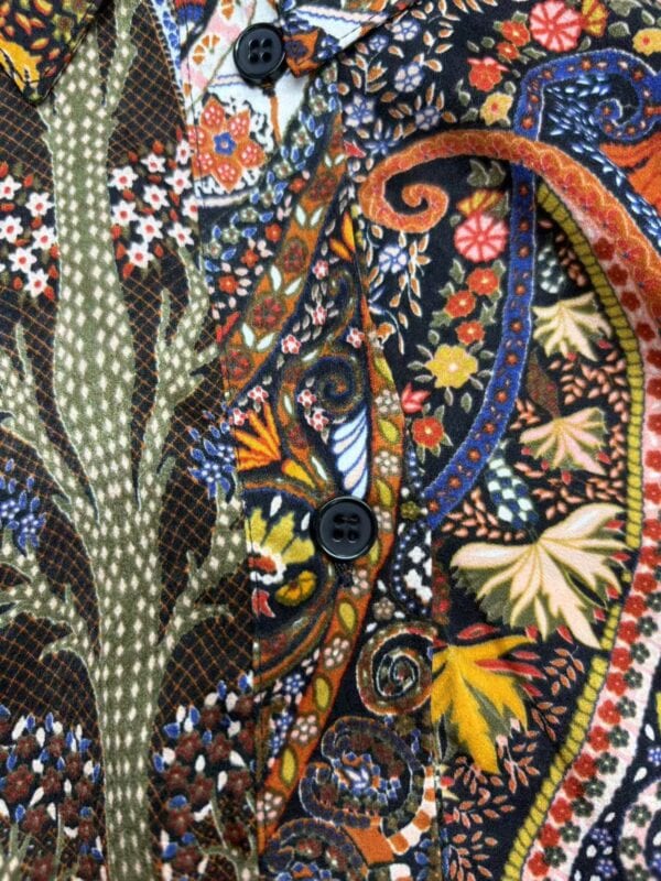 Close-up of a vibrant, floral-patterned shirt with detailed embroidery, buttons, and a mix of bright colors including orange, yellow, blue, and green.