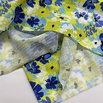 Close-up of colorful floral fabric featuring blue, yellow, and white flowers, ideal for fashion and clothing projects.