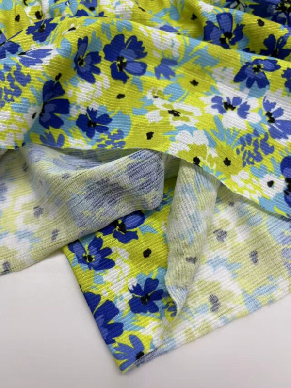 Close-up of colorful floral fabric featuring blue, yellow, and white flowers, ideal for fashion and clothing projects.