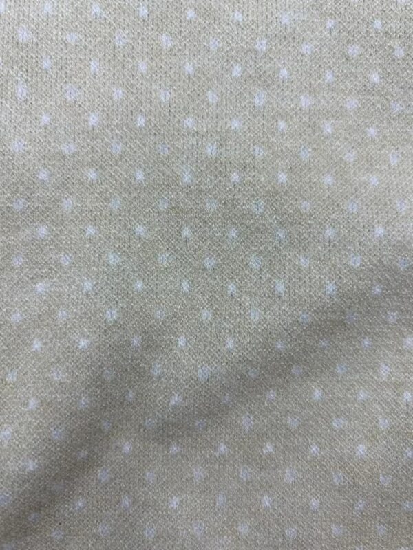 Close-up of beige fabric with small white polka dots, ideal for stylish clothing and accessories.