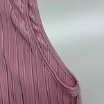 Close-up of a pink pleated dress fabric showcasing fine pleats and smooth texture, ideal for fashion and clothing design.
