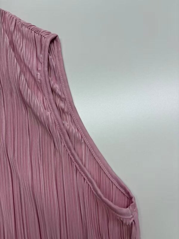 Close-up of a pink pleated dress fabric showcasing fine pleats and smooth texture, ideal for fashion and clothing design.