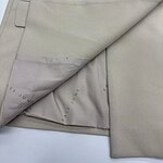 Close-up of beige suit fabric showing detailed stitching, buttons, and lining for high-quality tailoring and fashion design.