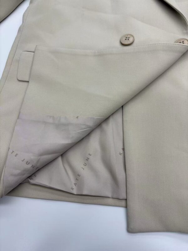 Close-up of beige suit fabric showing detailed stitching, buttons, and lining for high-quality tailoring and fashion design.