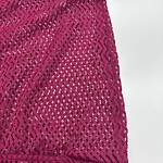 Close-up of vibrant pink lace fabric with intricate zigzag and floral patterns, ideal for stylish clothing and accessories.