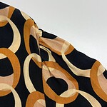 Close-up of a stylish fabric with a bold geometric pattern in black, beige, and orange tones, showcasing high-quality material and design.