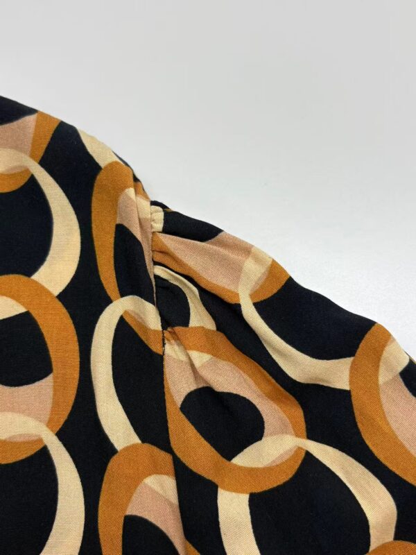 Close-up of a stylish fabric with a bold geometric pattern in black, beige, and orange tones, showcasing high-quality material and design.