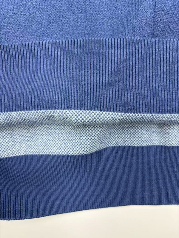 Close-up image of a blue knitted fabric with textured stripes, showcasing the detailed stitching and material quality.