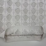 Close-up of a cream-colored knit sweater featuring a detailed geometric pattern and ribbed hem, perfect for stylish winter wear.