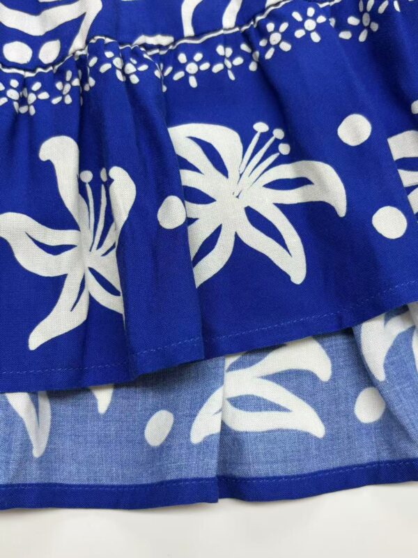 Close-up of vibrant blue fabric with white floral and dotted patterns, showcasing detailed textile design for fashion or home decor.