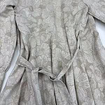 A stylish women's dress with a subtle floral pattern, featuring a waist tie and long sleeves, perfect for formal or casual occasions.