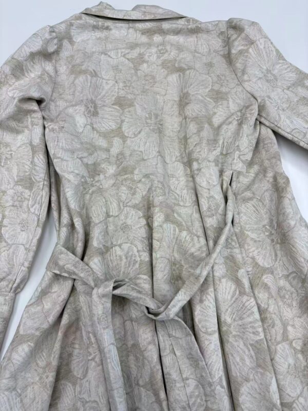 A stylish women's dress with a subtle floral pattern, featuring a waist tie and long sleeves, perfect for formal or casual occasions.
