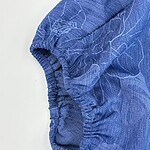 Close-up of a blue fashion garment featuring an elastic cuff and subtle line patterns, highlighting fabric texture and design details.
