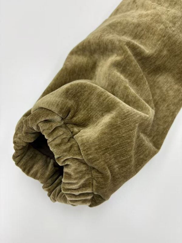 Close-up of a brown velvet sleeve with elastic cuff, showcasing soft texture and luxurious fabric for fashion and clothing design.