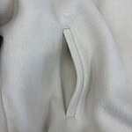 Close-up of a white fleece jacket featuring a sleek, zippered pocket for a stylish and functional look.
