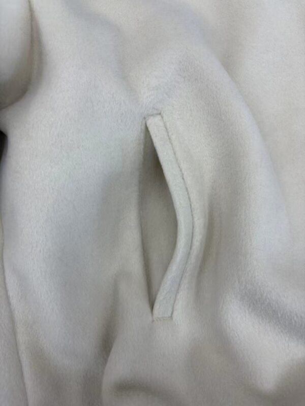 Close-up of a white fleece jacket featuring a sleek, zippered pocket for a stylish and functional look.