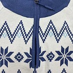 Close-up of a blue and white Nordic pattern sweater with a zipper collar, featuring snowflake and geometric designs, ideal for winter fashion.