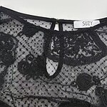 Close-up of a black lace top with floral patterns, featuring a keyhole neckline and delicate embroidery, perfect for stylish evening wear.