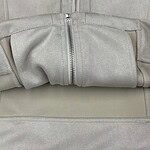 Close-up of a light grey fabric bag with a silver zipper, showing detailed stitching and material texture.