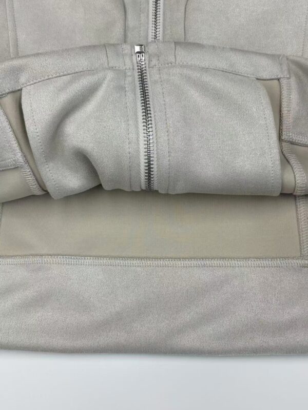 Close-up of a light grey fabric bag with a silver zipper, showing detailed stitching and material texture.