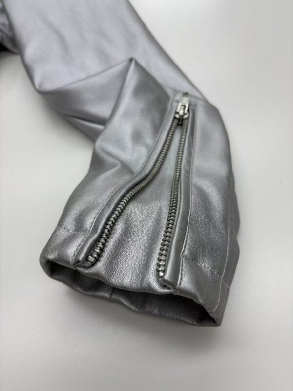 Close-up of a silver leather jacket sleeve featuring prominent silver zippers, showcasing modern fashion and high-quality craftsmanship.