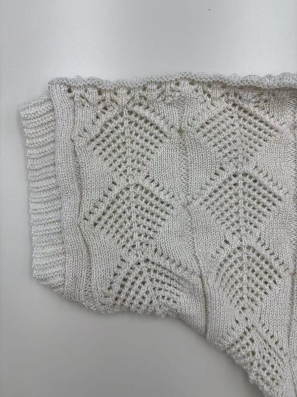 Close-up of a beautifully crafted white knitted lace blanket with intricate geometric patterns, perfect for home decor or as a cozy accessory.