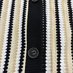 Close-up of a women's striped knit cardigan featuring black, white, and beige vertical lines with black buttons.