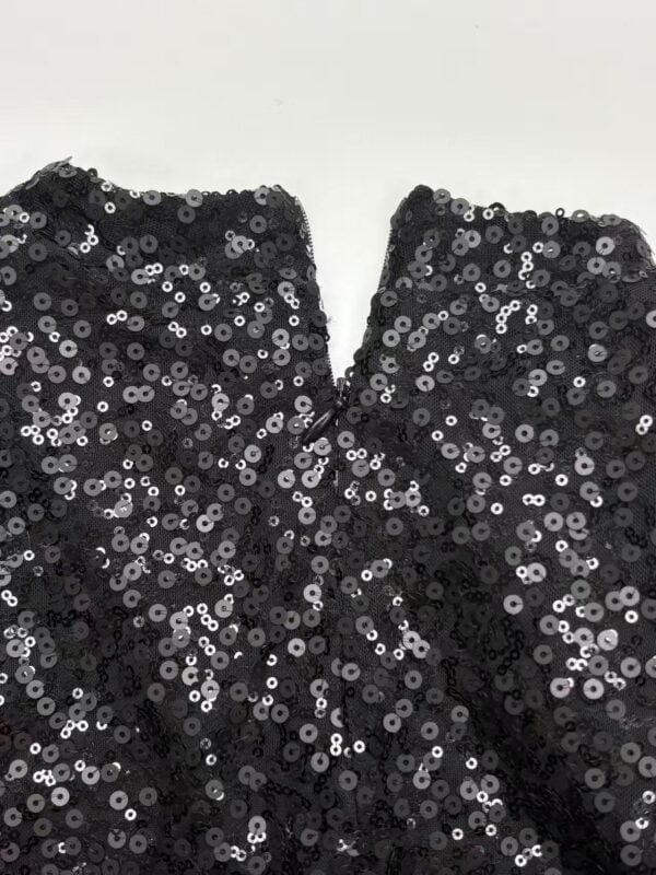 Close-up of black sequin fabric with shiny, reflective sequins for stylish clothing and accessories.