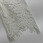 Close-up of intricate white lace fabric with floral patterns and fringed edges, ideal for fashion and wedding dress design.