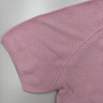 Close-up of a pink women's T-shirt showing fabric texture and stitching details.