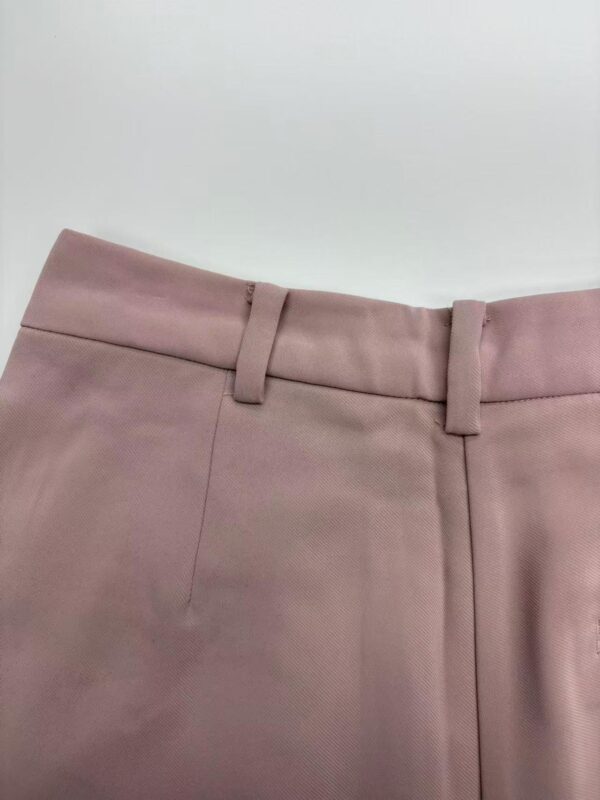 Close-up of stylish pink dress pants with belt loops, tailored fit, and smooth fabric, ideal for office or formal occasions.
