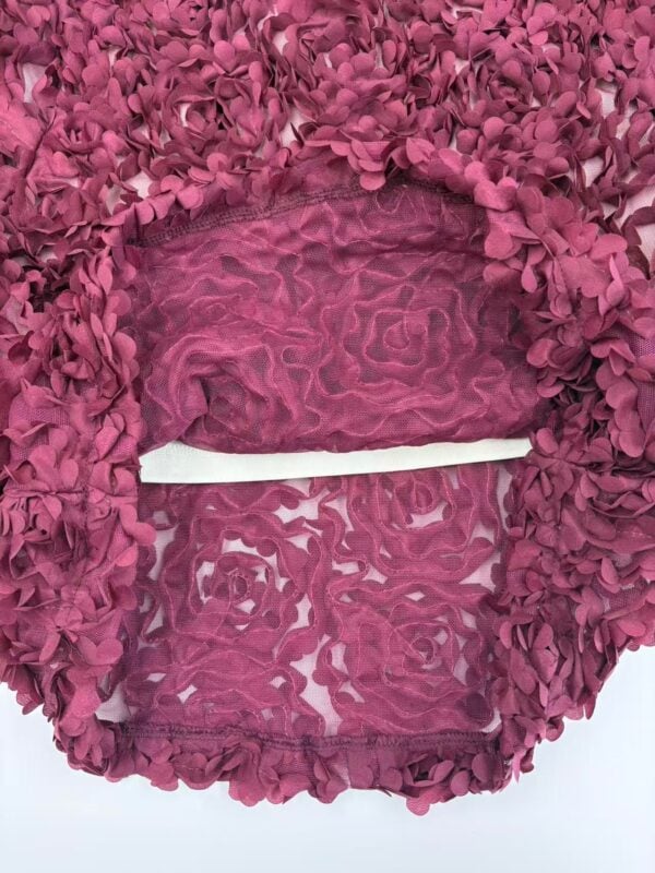Close-up of a pink floral lace dress with intricate embroidery and sheer fabric details, perfect for special occasions.